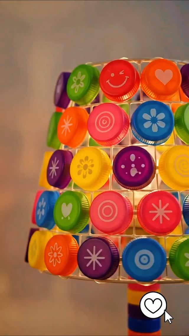 24 Art from Bottle Caps Ideas for Home, Gifts and Play 14 Colorful plastic bottle cap lampshade with printed symbols glowing from an internal light source.