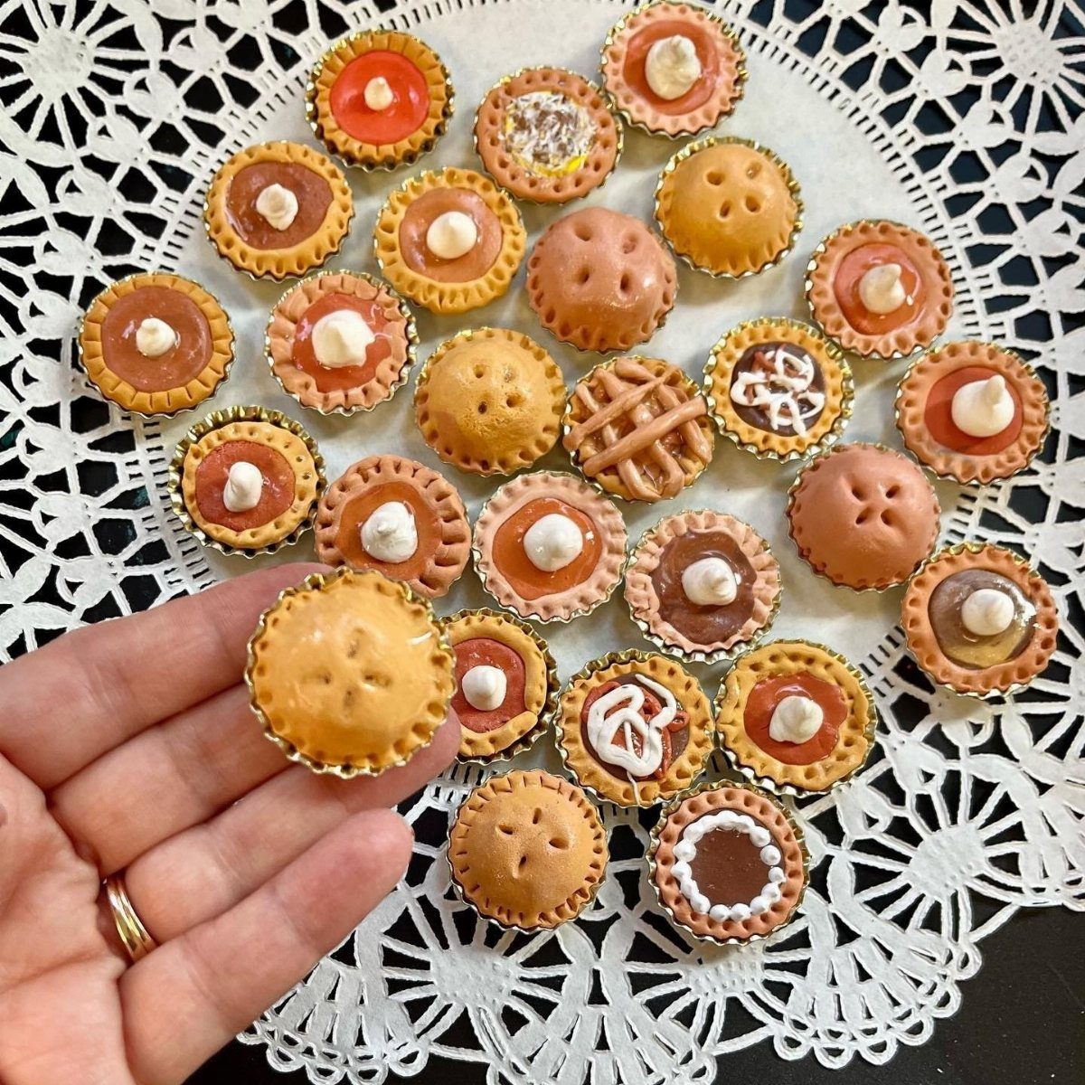 24 Art from Bottle Caps Ideas for Home, Gifts and Play 13 Miniature pies made from bottle caps and clay arranged on a white lace doily.