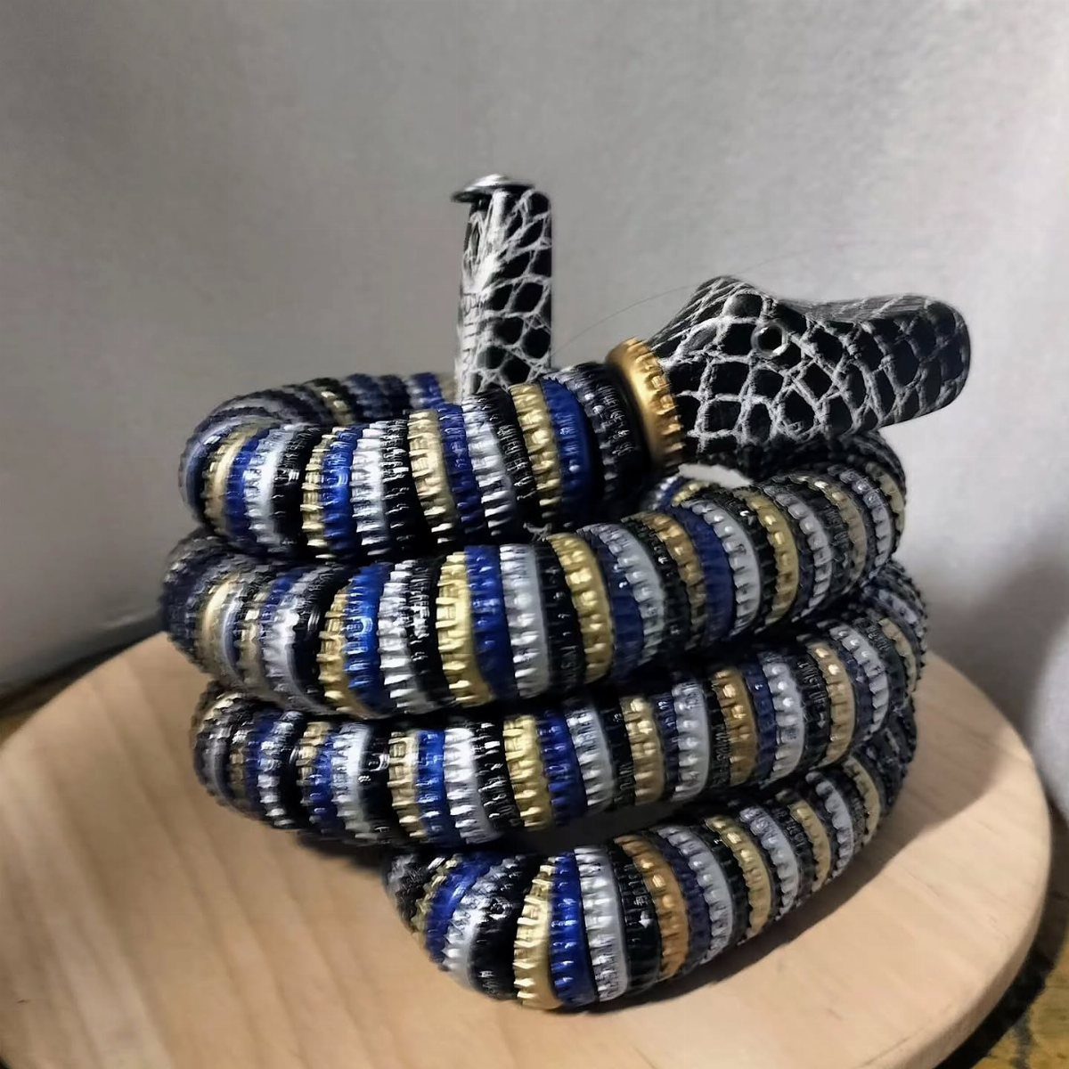24 Art from Bottle Caps Ideas for Home, Gifts and Play 12 Coiled snake sculpture made from blue, gold, and silver painted bottle caps.
