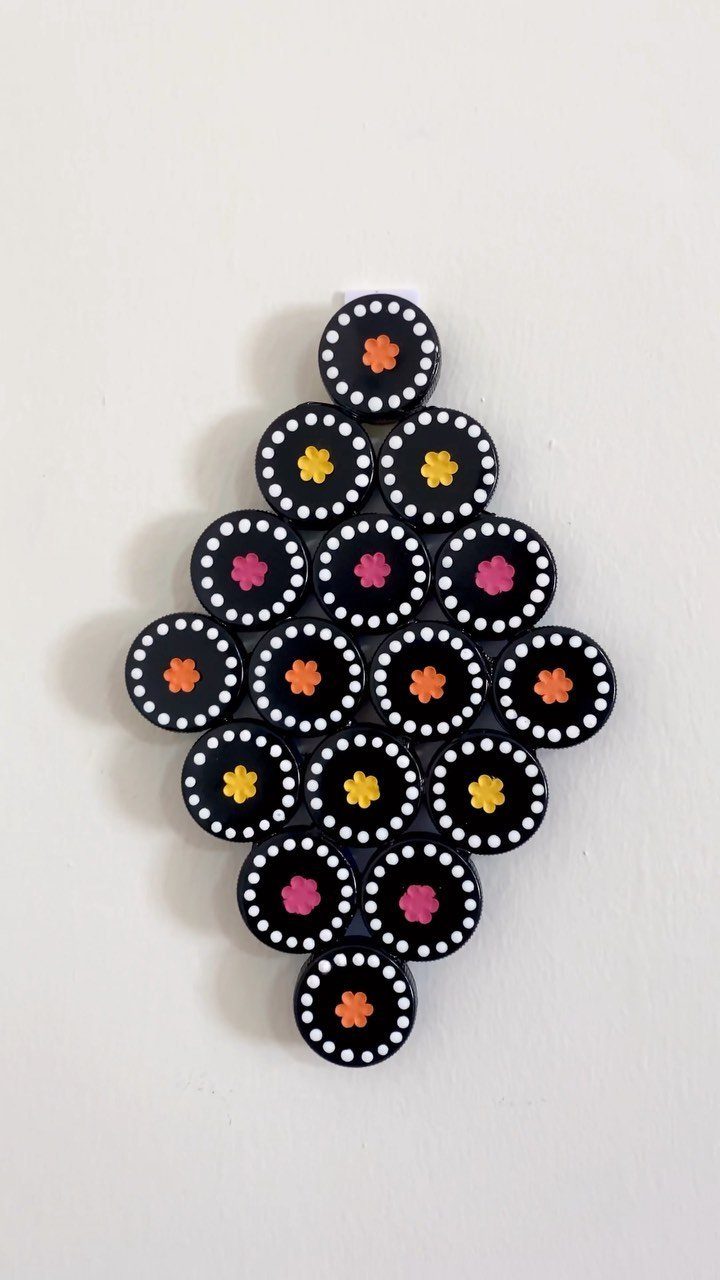 24 Art from Bottle Caps Ideas for Home, Gifts and Play 1 Diamond-shaped wall art made from black bottle caps with colorful flower centers.