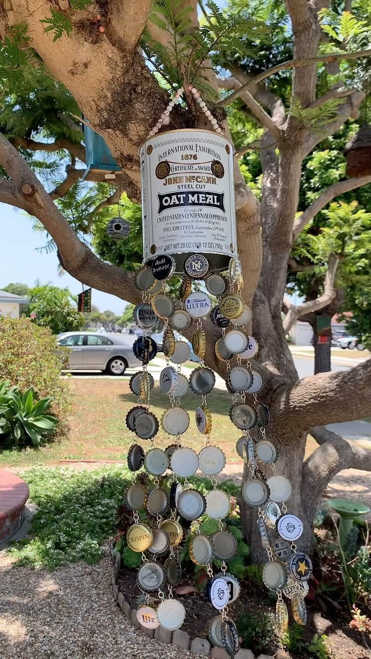 24 Art from Bottle Caps Ideas for Home, Gifts and Play 6 Bottle cap windchime hanging from a vintage oatmeal tin on a tree branch.