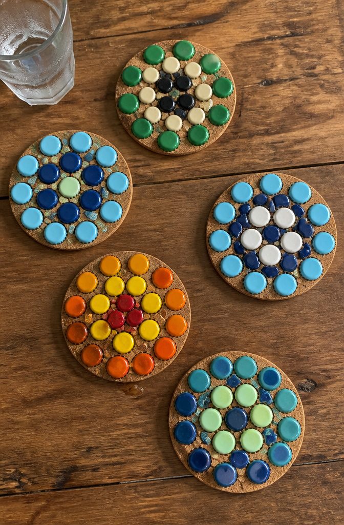 15 Bottle Cap Crafts and Ideas for Kids and Adults 5 Coasters made from painted bottle caps arranged on a cork base.