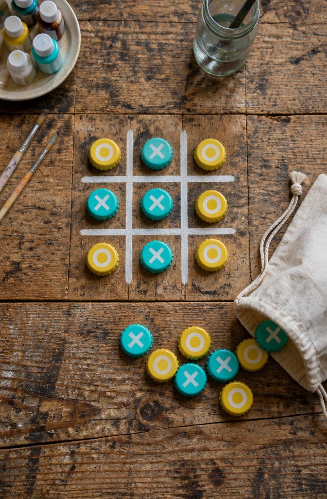 Bottle caps painted with symbols for a tic-tac-toe game.