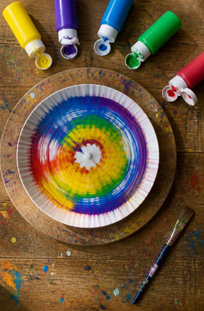 A spinning paper plate with colorful paint drips creating unique patterns.