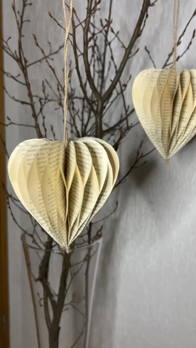 23 DIY Decor with Paper Projects for Every Room 14 Heart-shaped ornaments made from folded book pages hanging from bare tree branches.