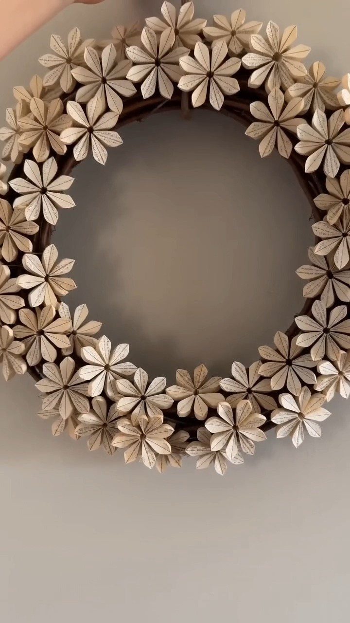 23 DIY Decor with Paper Projects for Every Room 6 Circular wreath with cream-colored book page flowers on a dark vine base.