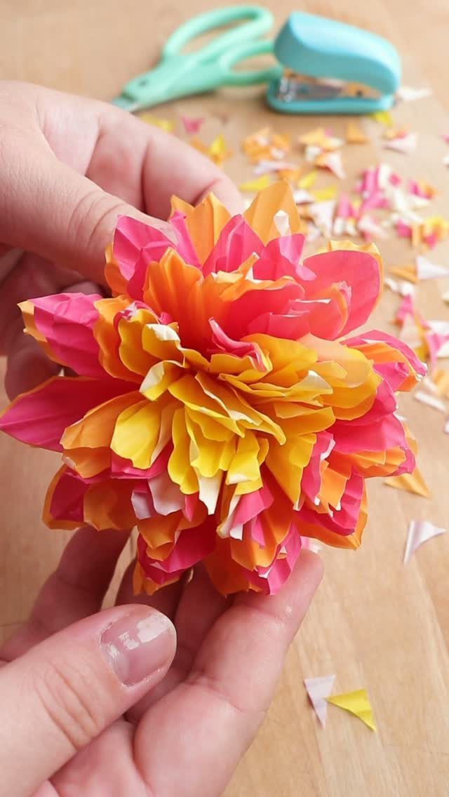 23 DIY Decor with Paper Projects for Every Room 10 Colorful flower made from pink and yellow cupcake liners held in two hands.
