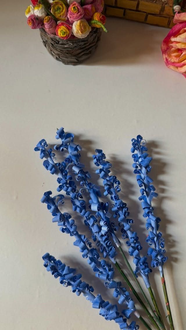 23 DIY Decor with Paper Projects for Every Room 21 Blue curled paper flowers on green stems resting on a white surface