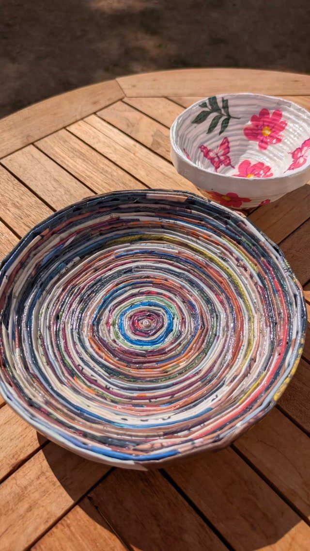 23 DIY Decor with Paper Projects for Every Room 4 Two colorful coiled paper bowls sitting on a wooden slatted outdoor table.