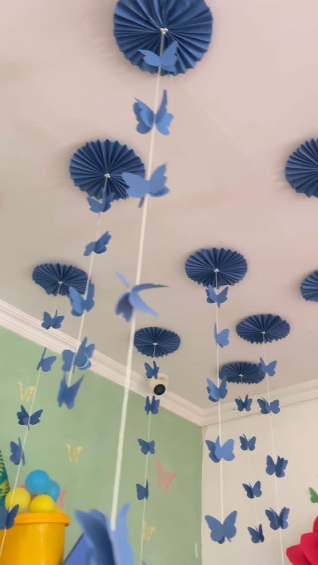23 DIY Decor with Paper Projects for Every Room 2 Blue paper fans and butterflies hanging as mobiles from a white ceiling.