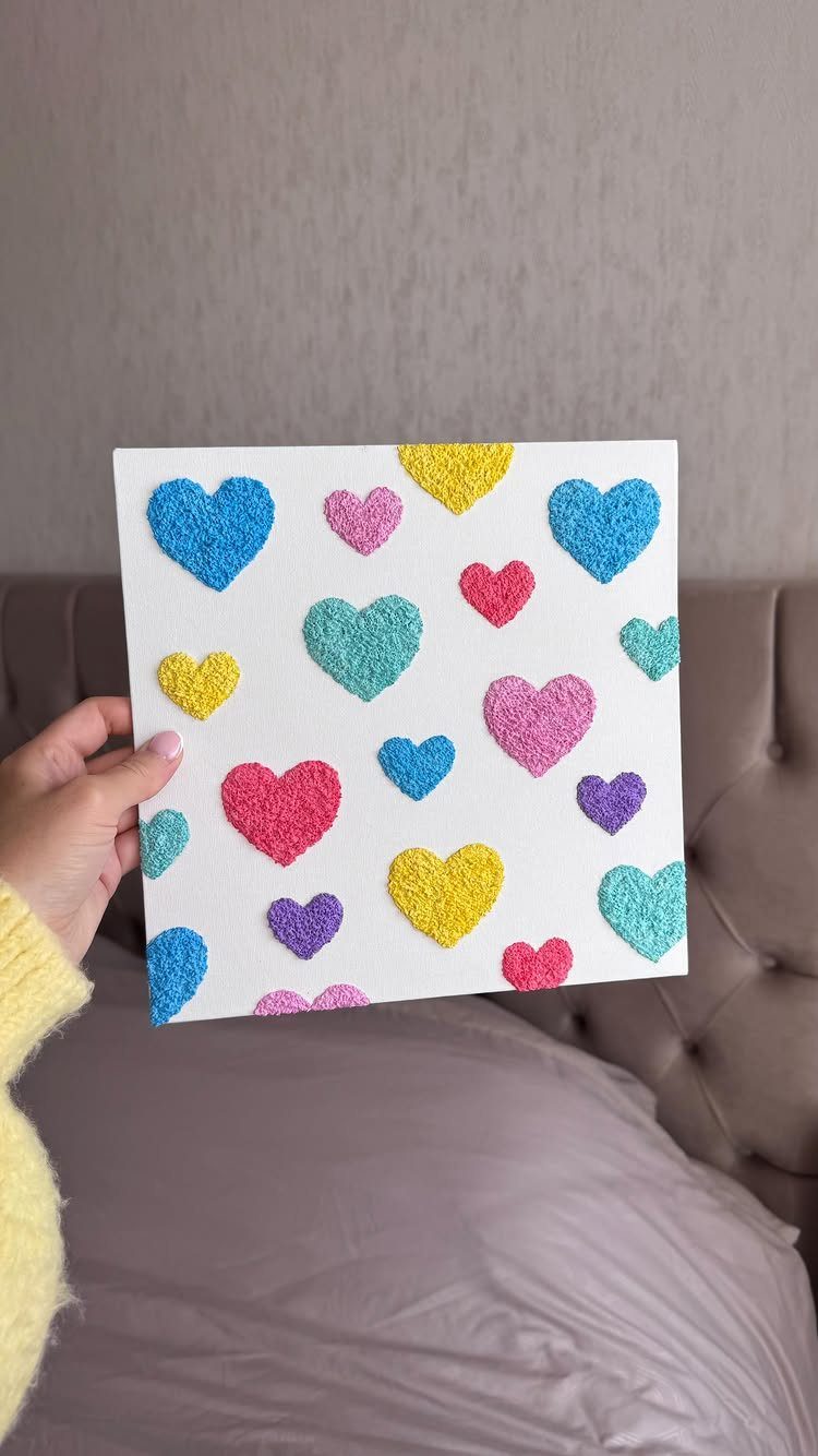 23 DIY Decor with Paper Projects for Every Room 9 Colorful textured tissue paper hearts on a white canvas held by a hand.