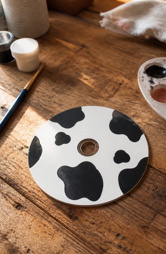 A CD featuring a cow print design with black and white.