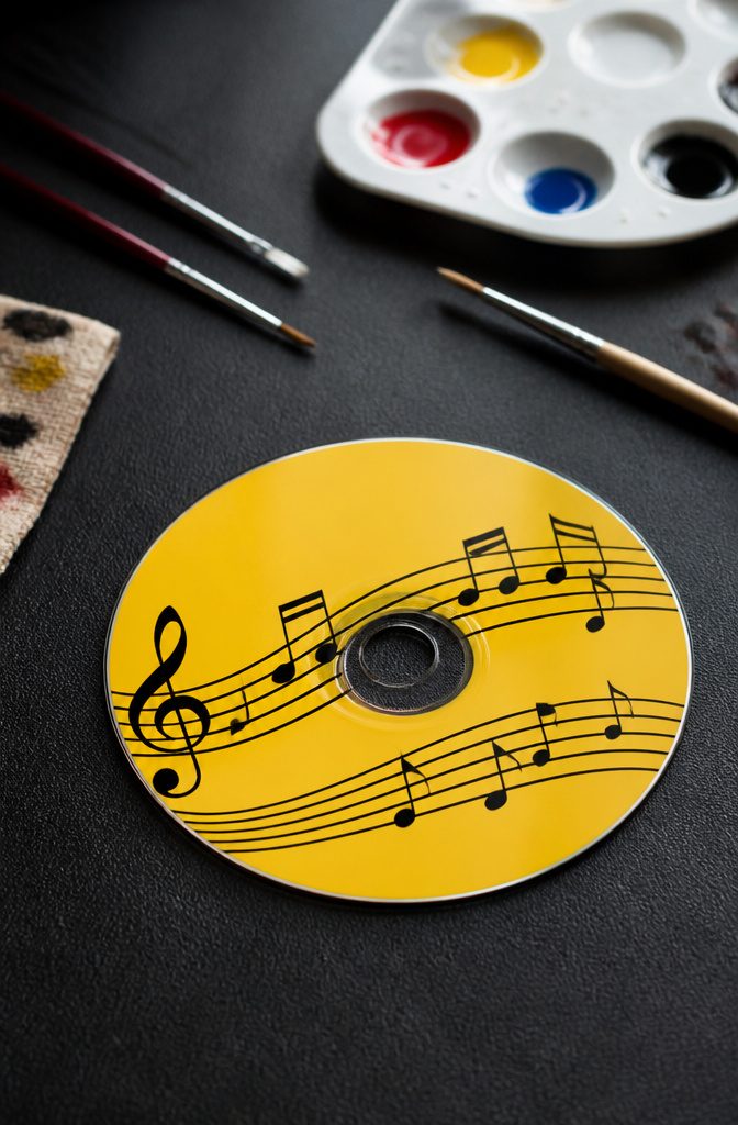 A CD decorated with black music notes on a yellow background.
