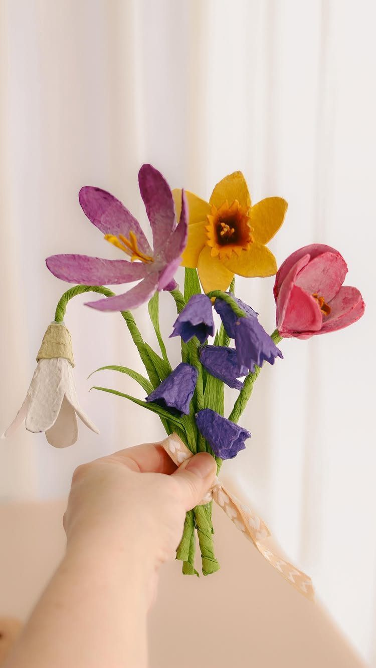 17 Recycled Art Projects for Kids and Adults to Make 4 Hand holding a bouquet of colorful flowers crafted from recycled egg cartons.