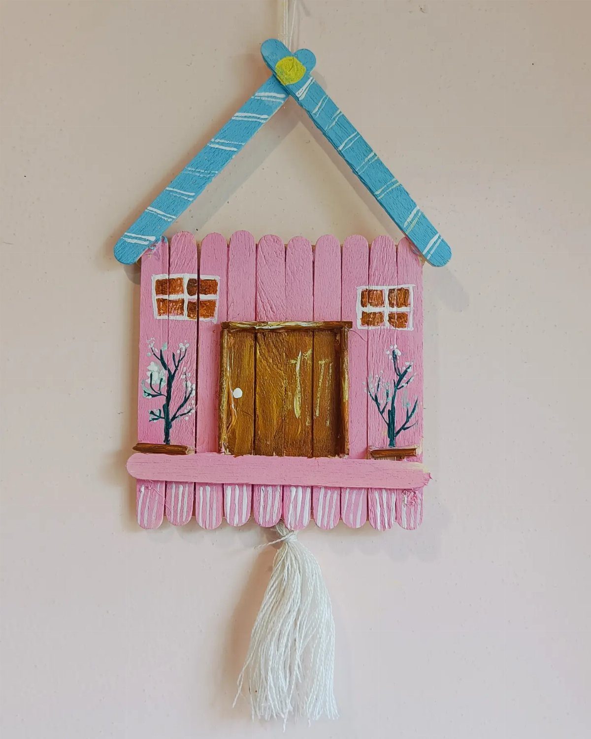 17 Recycled Art Projects for Kids and Adults to Make 7 Popsicle stick house craft with pink walls and blue roof hanging on wall