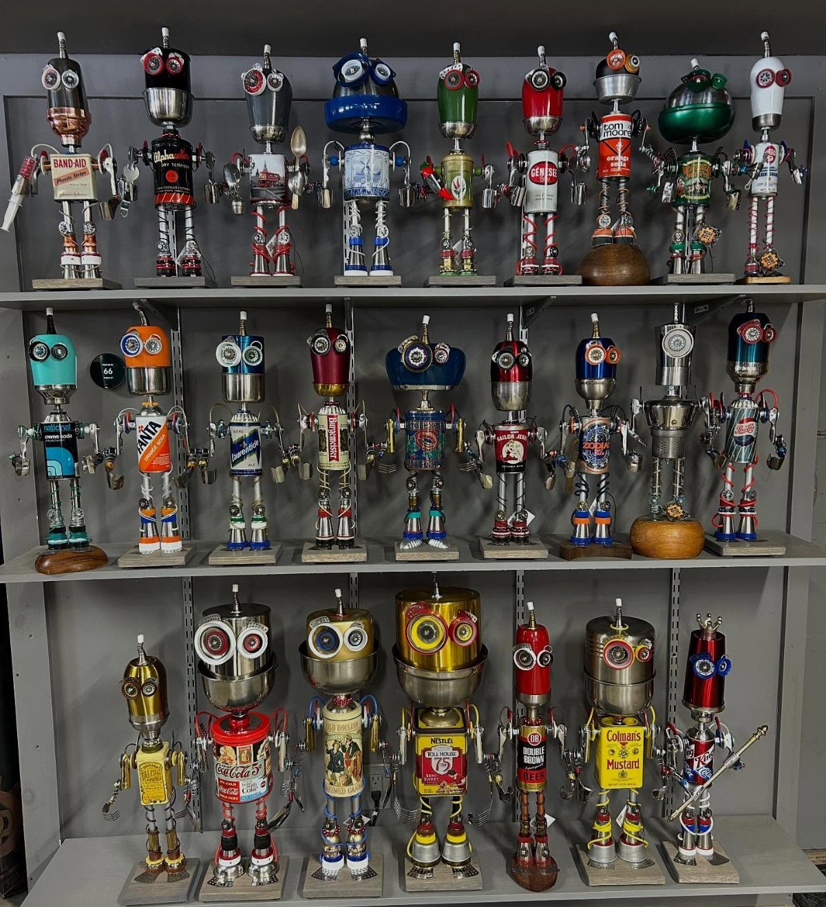 17 Recycled Art Projects for Kids and Adults to Make 11 Recycled metal robot figures made from cans and bolts on grey shelves