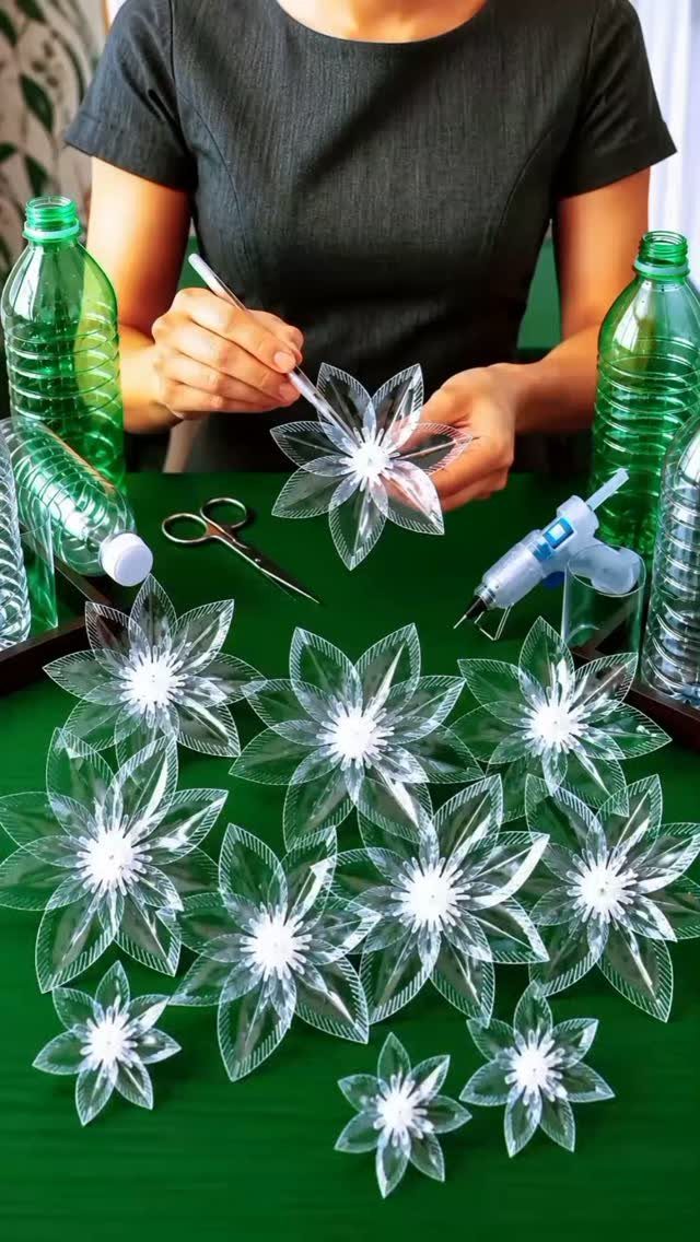 17 Recycled Art Projects for Kids and Adults to Make 9 Clear plastic flowers made from water bottles on a green table with tools.